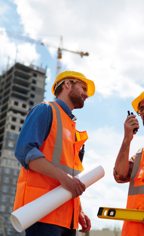 Contractor speaking on walkie-talkie with co-worker near by